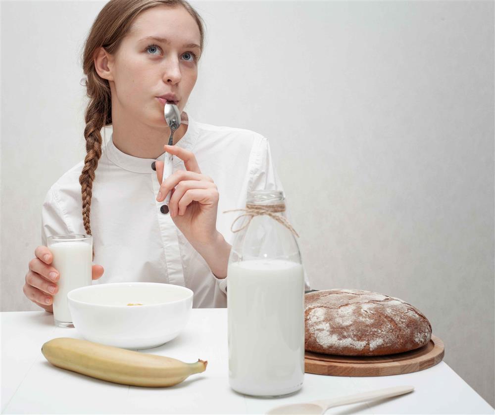 A girl with a glass of milk in her hand and thinking